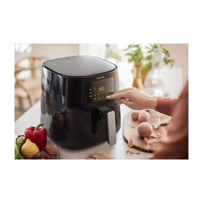 سرخ کن فیلیپس مدل HD9270 روی میز قرار دارد سیاه رنگ و کنار فلفل دلمه ای ها